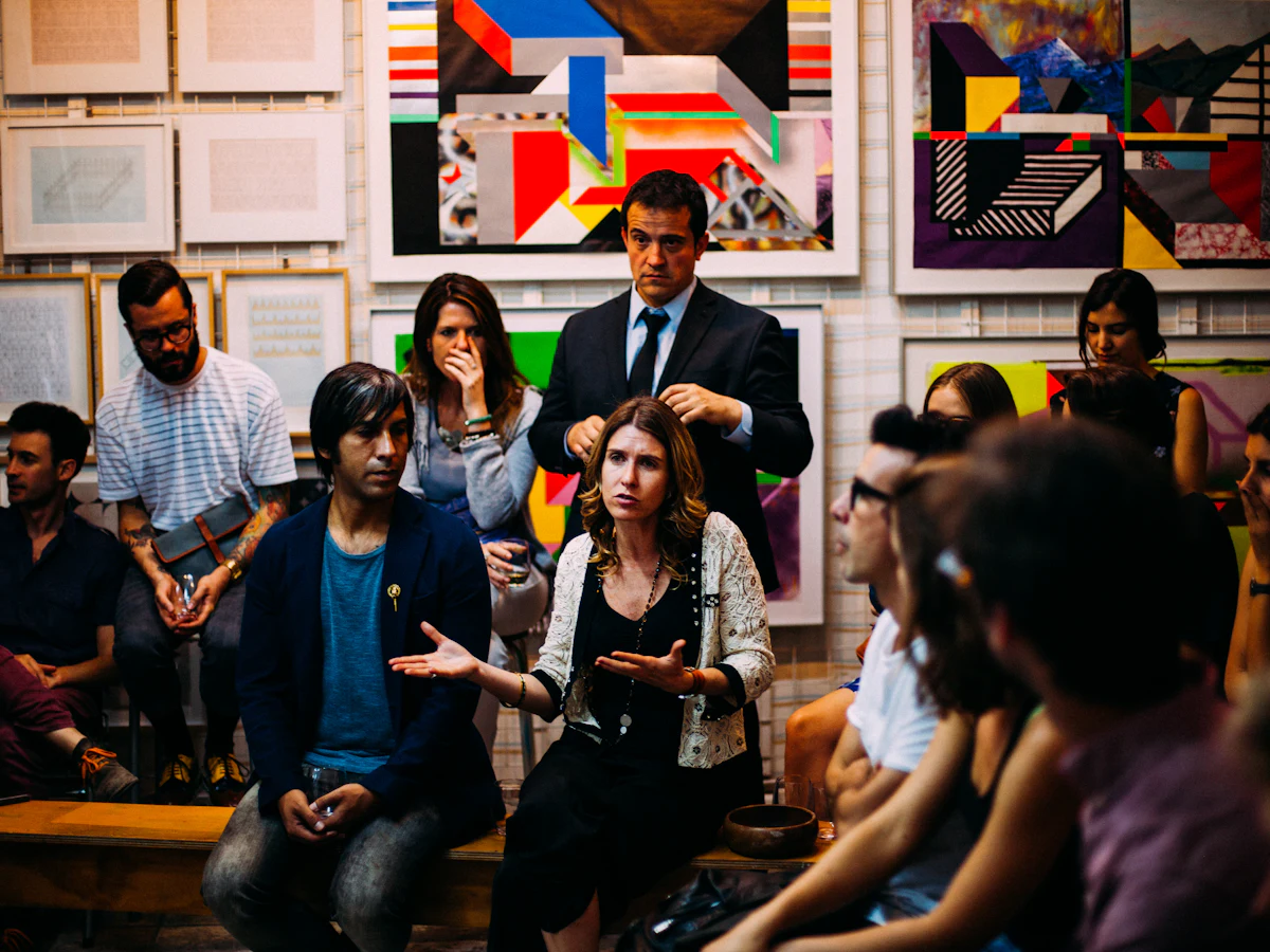 Une assemblée qui discute, assise en cercle dans une salle décorée de tableaux