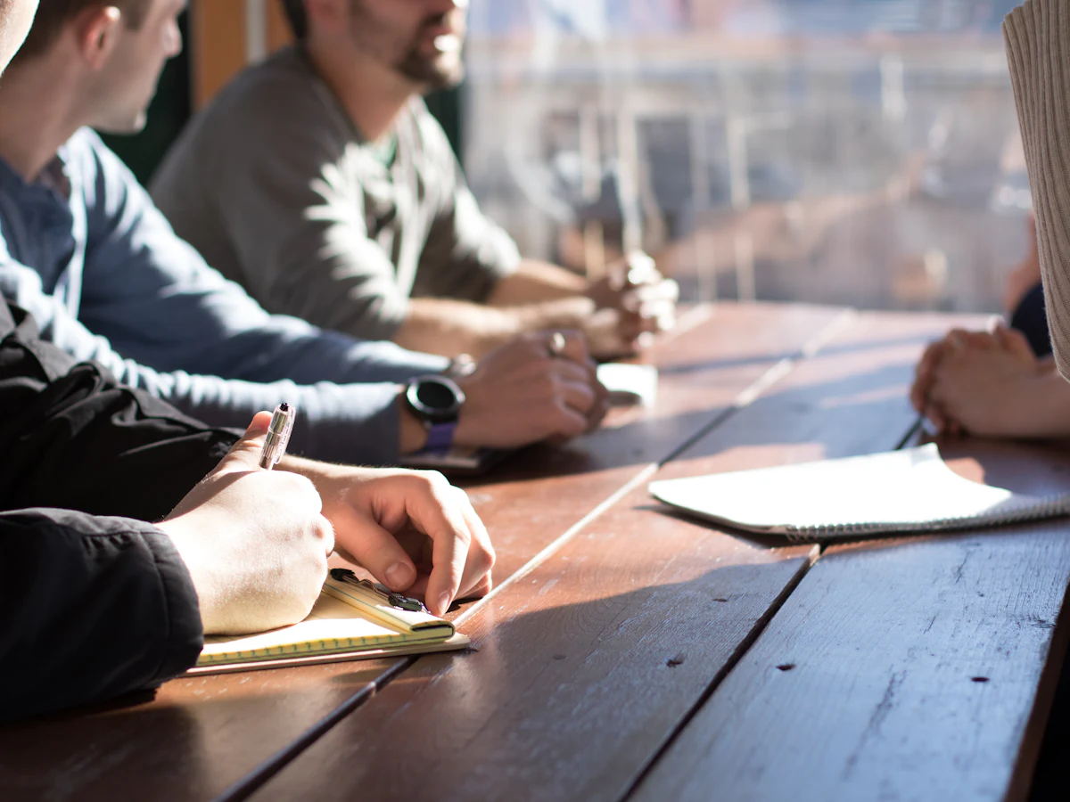 Des personnes autour d'une table en bois qui prennent des notes
